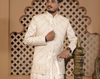 May include: A white patterned blazer with a mandarin collar and a long zipper. The blazer has a subtle sheen and is worn by a person standing in front of a decorative wall.