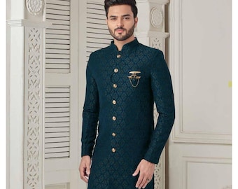 May include: A teal blue patterned kurta with a button-up front and a gold pin. The kurta has a mandarin collar and long sleeves.