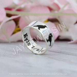 Könnte beinhalten: Ein silberner Ring mit einer schwarzen Vogelsilhouette und der Inschrift "Kyle 7/8/0".