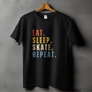 May include: Black t-shirt with a vintage-style graphic that reads "Eat. Sleep. Skate. Repeat."