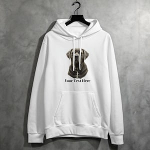 Puede incluir: Sudadera con capucha blanca con un gran gráfico de la cara de un perro en tonos grises y marrones. El texto "Your Text Here" está impreso debajo de la imagen del perro. La sudadera tiene capucha, bolsillo delantero y cordones.
