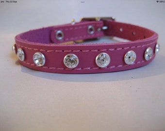 Puede incluir: Un collar de perro de cuero rosa con detalles de diamantes de imitación transparentes.