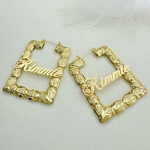 May include: Gold hoop earrings with a square frame and the names "Kimmie" and "Rimme" written in cursive.