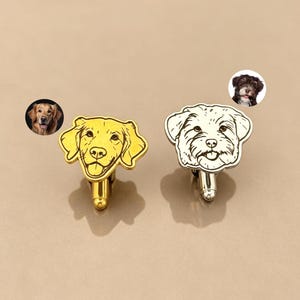 May include: Two metal cufflinks featuring engraved dog portraits. The left cufflink is gold-toned with a golden retriever design, while the right cufflink is silver-toned with a shaggy-haired dog design. Each is paired with a small circular photo.