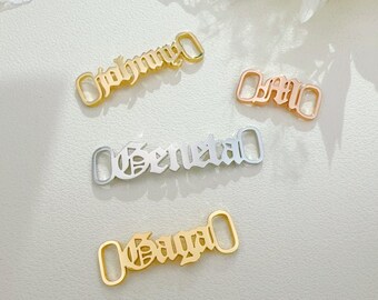 May include: Four gold-tone metal shoe charms with different names: "Johnny", "Bria", "Geneva", and "Kayla".