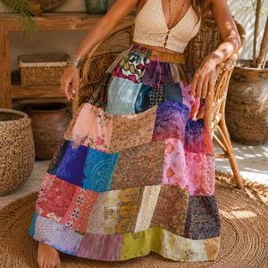 May include: A cream-colored crochet halter top with a front button closure paired with a floor-length patchwork skirt featuring a variety of colorful floral, paisley, and geometric patterns in shades of pink, blue, purple, yellow, and green.
