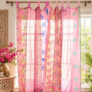 Può includere: Un set di tende a tutta altezza caratterizzato da pannelli verticali in vari tessuti rosa. I pannelli presentano motivi diversi, tra cui disegni floreali, geometrie complesse e sezioni rosa a tinta unita con piccoli ricami color turchese.