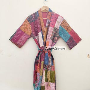 May include: A colourful patchwork robe, featuring pink, orange, blue, and green squares stitched together. The robe has a tie belt. The text "Artist Couture" is visible on the robe.