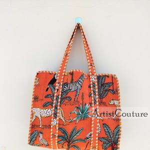 May include: Orange tote bag with a white and black zebra, leopard, toucan, and flamingo print. The bag has orange and white striped straps and a white trim.