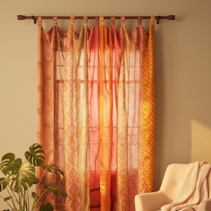 Peut inclure: Rideaux aux motifs orange et jaune suspendus à une tringle en bois. Les rideaux sont en tissu transparent, laissant filtrer la lumière. Une plante en pot et une chaise sont au premier plan.