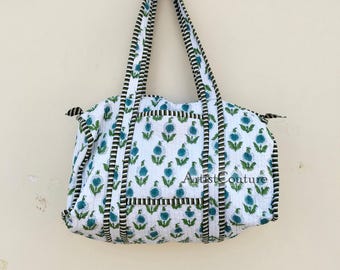 Könnte beinhalten: Weiße Baumwoll-Tragetasche mit blauem und grünem Blumendruck und schwarz-weiß gestreiftem Besatz. Die Tasche hat zwei Henkel und der Text "Artist Couture" ist auf der Vorderseite sichtbar.