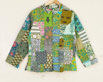 Puede incluir: Chaqueta patchwork con cuello mandarín, con una variedad de patrones de tela en tonos verdes, azules, rosas y grises. La chaqueta está colgada en una percha de madera sobre un fondo neutro. El texto "Artist Couture" es visible.