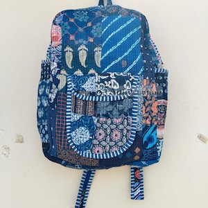 Puede incluir: Una mochila acolchada de patchwork azul y blanco con cierre de cremallera y correas ajustables.