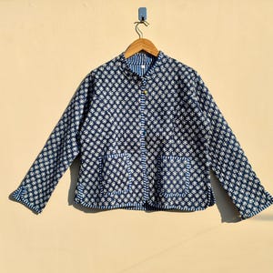 Puede incluir: Una chaqueta acolchada con estampado azul y blanco, cierre de botón y dos bolsillos.