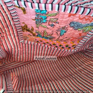 May include: Interior view of a quilted tote bag. The bag features a pink and white striped lining and a decorative patch with floral and butterfly patterns. The bag's interior is visible, showcasing the fabric's texture and design.