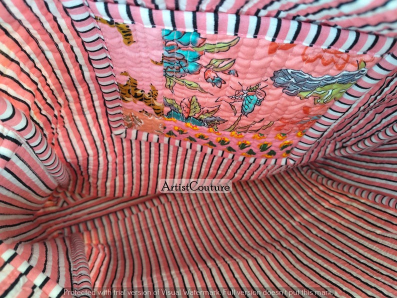 May include: Interior view of a quilted tote bag. The bag features a pink and white striped lining and a decorative patch with floral and butterfly patterns. The bag's interior is visible, showcasing the fabric's texture and design.