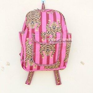 May include: Pink striped backpack with a tiger print. The backpack has a large main compartment and two smaller pockets on the front. The straps are adjustable and have a tiger print.