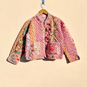 Może przedstawiać: Różowa pikowana kurtka z kwiatowym nadrukiem. Kurtka zapinana na guziki i posiada dwie kieszenie.