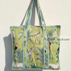 Peut inclure: Un sac cabas matelassé vert avec un motif animalier noir et blanc. Le sac a une longue poignée et une fermeture éclair. Le sac est en coton et est parfait pour transporter les essentiels du quotidien.