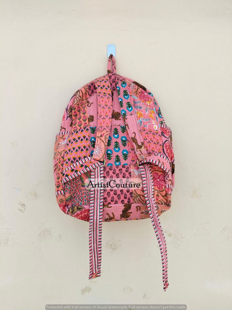 May include: Pink backpack with a patchwork design featuring floral and animal patterns. The backpack has adjustable straps and a top handle. The text "Artist Couture" is visible on the front.