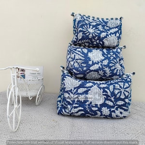 Può includere: Tre pochette in tessuto blu e bianco con motivo floreale impilate l'una sull'altra. Le pochette sono in cotone e hanno una texture trapuntata. Le pochette sono decorate con un motivo floreale bianco su sfondo blu. Le pochette sono perfette per riporre piccoli oggetti come gioielli, trucco o articoli da toeletta.