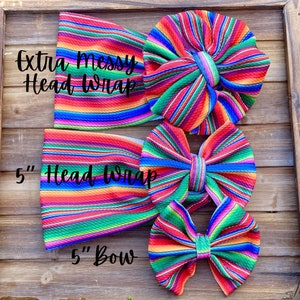 May include: Three colorful striped fabric headbands and bows. The largest headband is labeled "Extra Messy Head Wrap". The medium headband is labeled "5" Head Wrap". The smallest bow is labeled "5" Bow".