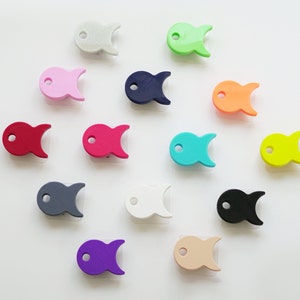 May include: A set of 13 colorful fish-shaped silicone teethers in various colors, including pink, blue, green, yellow, red, orange, purple, gray, white, and black. The teethers are designed for babies and toddlers to help soothe sore gums during teething.