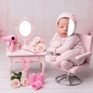 May include: A baby in a pink outfit and hat sits in a pink salon chair. A miniature pink vanity with a mirror, hair dryer, and styling tools sits nearby. Pink roses and curlers complete the scene, creating a soft, feminine aesthetic.