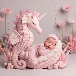 Könnte beinhalten: Ein Neugeborenes in rosa Outfit und Mütze ruht in einer rosa Seepferdchen-förmigen Requisite mit einem Einhornhorn. Die Szene ist mit rosa Korallen und Blumen dekoriert und schafft ein skurriles Unterwassermotiv.