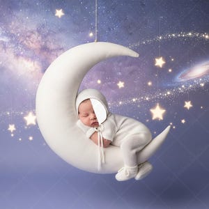May include: A baby in a white outfit and bonnet sleeps on a white crescent moon prop. The background is a starry night sky with a galaxy and twinkling stars. The image evokes a dreamy, celestial theme, perfect for newborn photography.