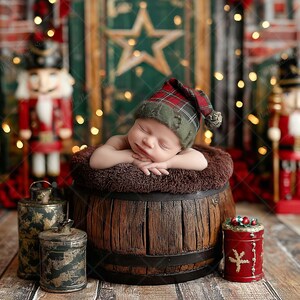 May include: A sleeping baby wearing a tartan hat rests in a wooden barrel with a soft, brown lining. The Christmas scene features nutcrackers, antique metal containers, and a red container with a festive design.