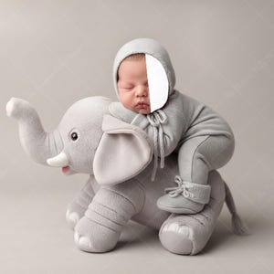 May include: A newborn baby wearing a gray knit outfit and matching bonnet is posed on a plush gray elephant toy. The elephant has large ears, a trunk, and a smiling expression. The background is a soft, neutral color.
