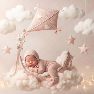 May include: A sleeping newborn in a pink knitted outfit and bonnet rests in a cloud-shaped bed. The scene is decorated with a pink kite, stars, and fluffy clouds, creating a soft, dreamy aesthetic. The overall theme is baby photography.
