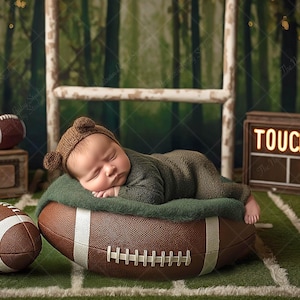 Könnte beinhalten: Ein schlafendes Baby in einem braunen Bärenhut und grünem Outfit liegt auf einem Football. Der Hintergrund zeigt ein grünes Feld, ein Holzschild mit "TOUCHDOWN!" und weitere American Footballs.