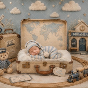 May include: A sleeping infant wearing a blue and white striped hat and onesie inside an open vintage suitcase with a world map interior. The scene includes a teddy bear in a conductor hat, a toy train, a Dreamland station, and a ticket reading First Class.