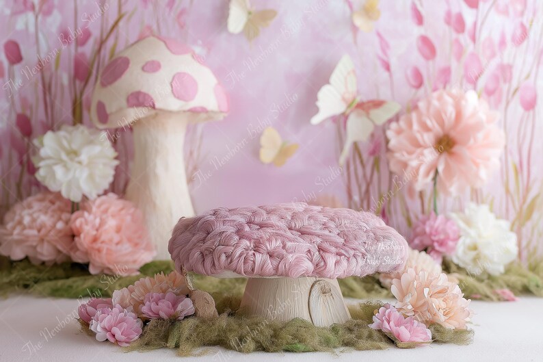 May include: A whimsical photography prop featuring a pink mushroom-shaped platform with a textured top, surrounded by flowers and butterflies. The backdrop is a soft pink with floral accents, creating a fairytale scene.