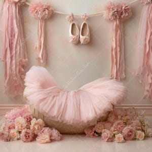May include: A soft pink newborn photography backdrop featuring a ruffled basket, tulle skirt, and floral accents. Delicate pink ribbons and baby shoes hang from a string, creating a dreamy, feminine scene.
