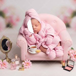 May include: A baby in a pink robe, towel, and booties is nestled in a miniature pink armchair. A cup of tea, a gold-framed mirror, perfume bottles, lipstick, and flowers are arranged around the chair, creating a spa-like theme.