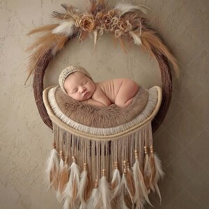 May include: A newborn baby wearing a knitted cap is peacefully sleeping on a soft, brown, crescent-shaped bed. The bed is suspended within a circular, woven wreath adorned with feathers and dried flowers, creating a bohemian aesthetic.