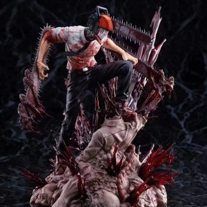 May include: A detailed figurine of a character with a chainsaw for a head, standing on a base of bloody flesh. The character is wearing a white shirt with a black tie and black trousers, and is covered in blood. The chainsaw is orange and black, and the base is a gruesome depiction of flesh and bone.