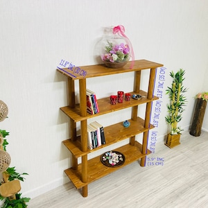 May include: A four-tier wooden shelf unit with a natural brown finish. The shelf is 13.8 inches wide and 11.8 inches deep. It is 5.9 inches tall.