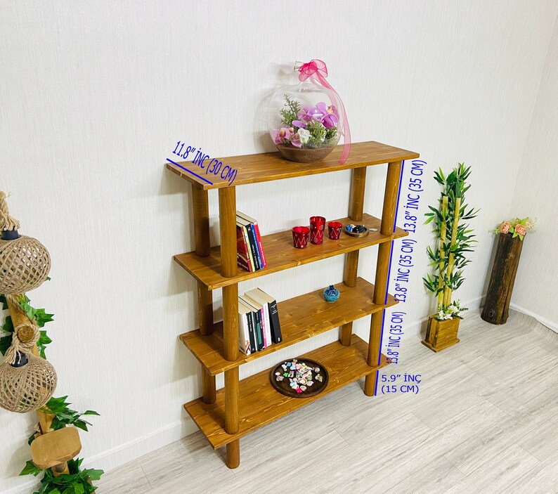 May include: A four-tier wooden shelf unit with a natural brown finish. The shelf is 13.8 inches wide and 11.8 inches deep. It is 5.9 inches tall.