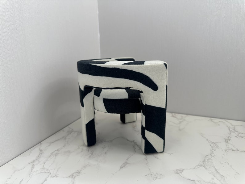 May include: A black and white zebra patterned stool with four legs. The stool is made of fabric and has a rounded top.