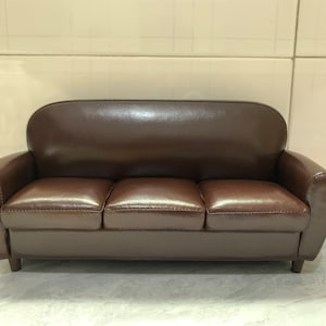 May include: A brown leather sofa with three cushions and a tufted back.