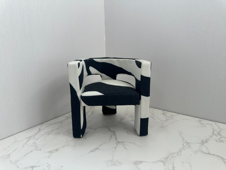 May include: A black and white zebra patterned armchair with a square shape and four legs.