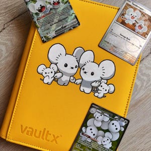Puede incluir: Una carpeta de cartas coleccionables de color amarillo brillante con el texto vaultx en relieve, que presenta un gráfico central de cuatro criaturas blancas parecidas a ratones. Dos cartas Maushold ex y una carta Tandemaus están sobre la cubierta.