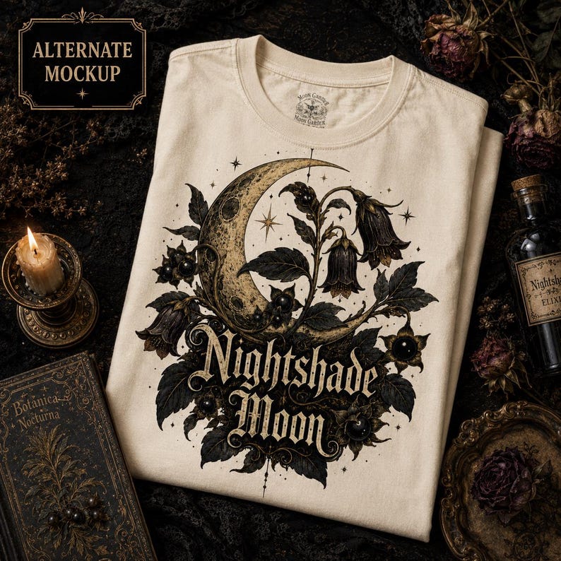 May include: A cream-colored t-shirt featuring a graphic print of a crescent moon surrounded by dark botanical elements and bell-shaped flowers. The text "Nightshade Moon" is printed in a decorative font below the moon and floral illustration.