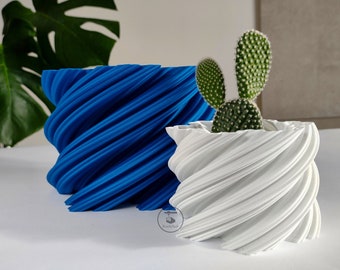 May include: Two spiral-designed planters, one blue and one white, with a small cactus in the white one. The planters have a textured finish and are suitable for indoor use. The design is modern and visually appealing. The planters are made of a durable material.