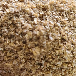 May include: Close-up of a pile of light brown wheat bran flakes.