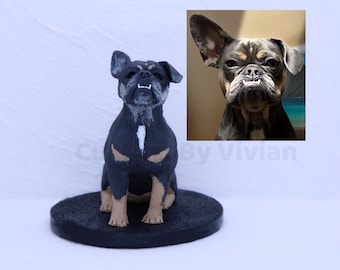 May include: A black and tan dog figurine with a white chest marking and tan paws. The dog is sitting on a black circular base. An image of the dog's face is in the upper right corner. The figurine is a decorative item.
